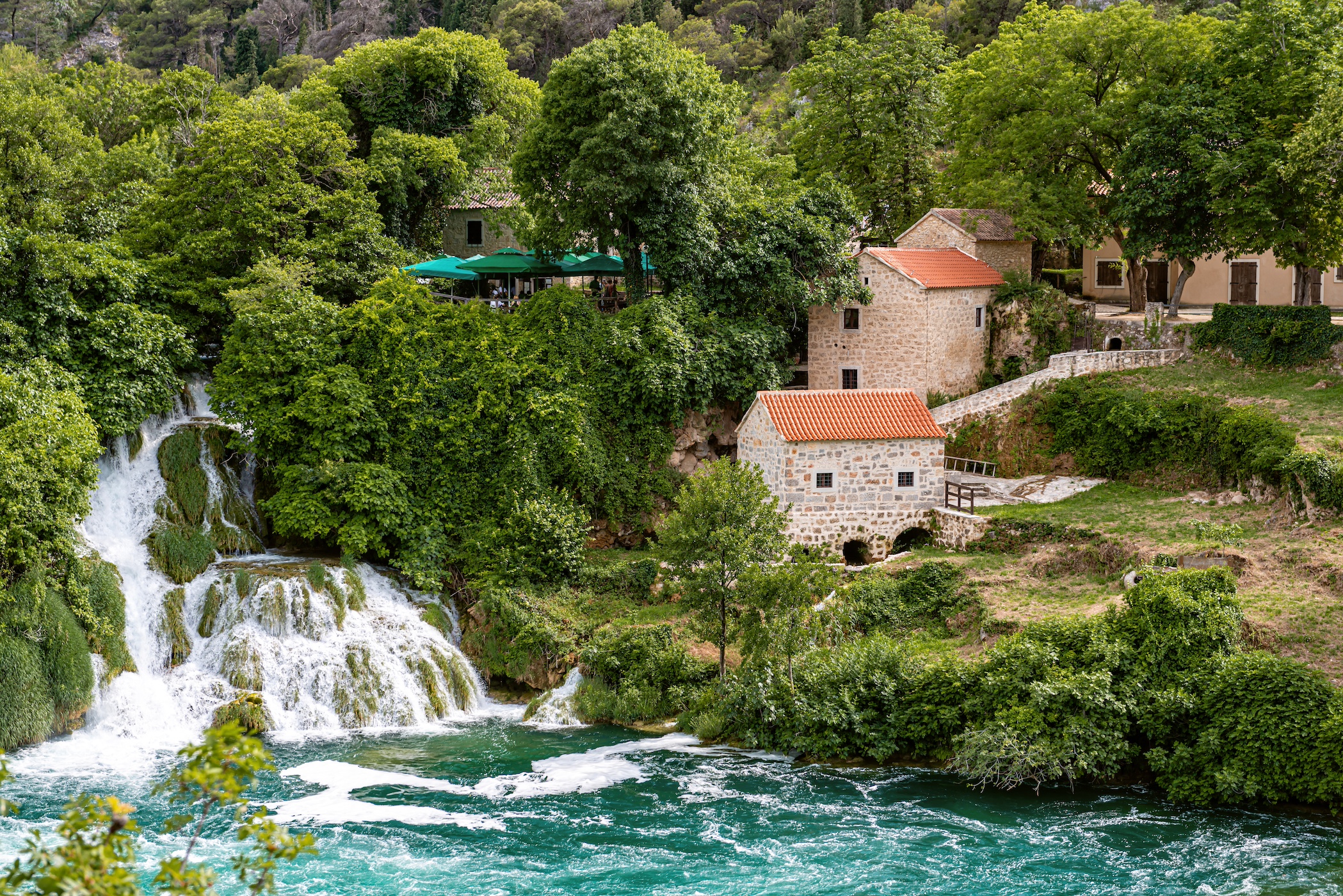 The Waterfalls of Krka National Park and stone mill building with orange tile roof, Croatia